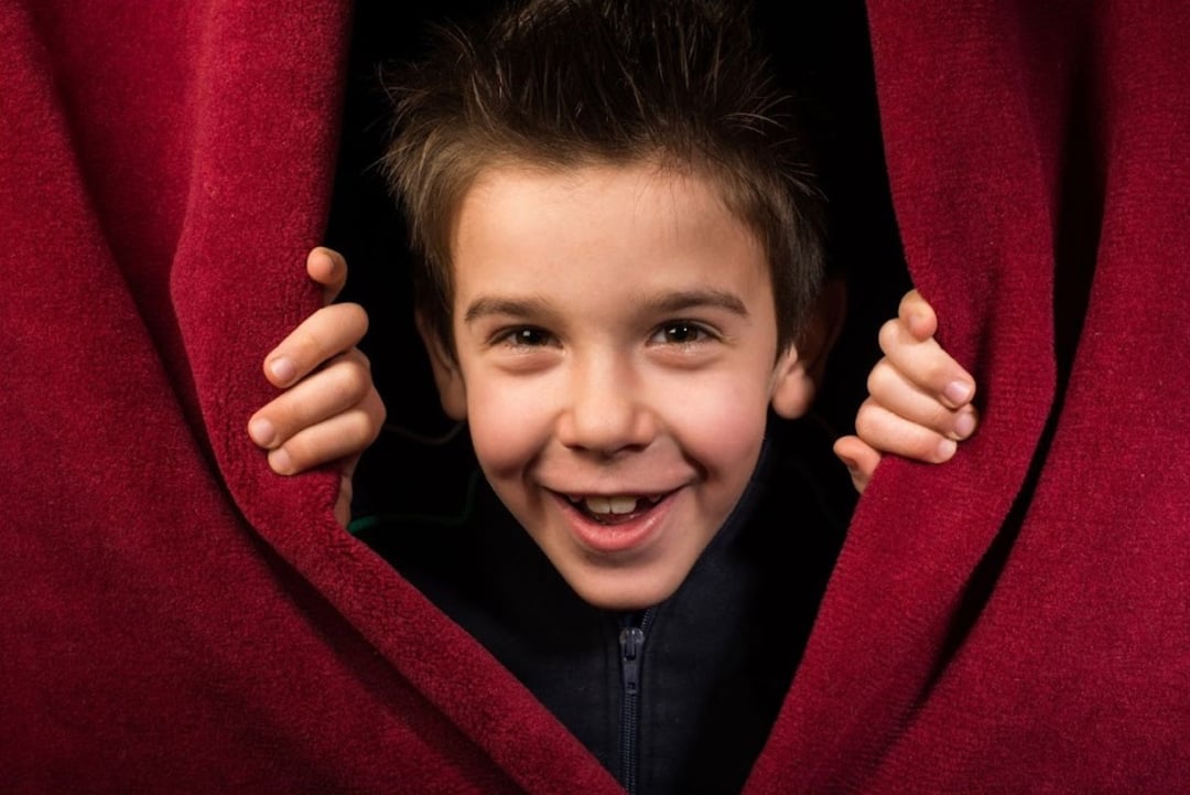 child appearing from behind theater curtains